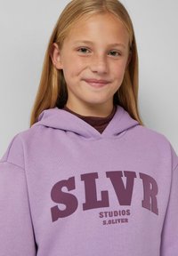 Felpa viola con grafica frontale che riporta "SLVR STUDIOS S.Oliver" in grassetto lettere color bordeaux. Ha una vestibilità comoda e un cappuccio con cordino.