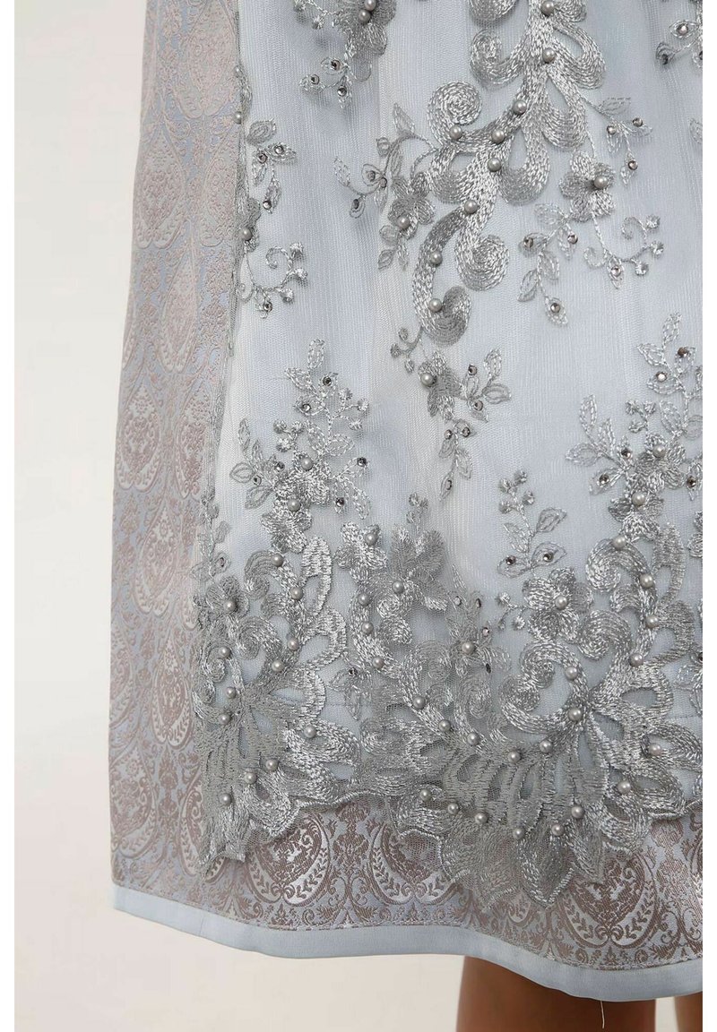 Helle blaue Stoff mit aufwendiger silberner Stickerei und Perlen. Das Design umfasst Blumenmuster und eine subtile Damaststruktur.