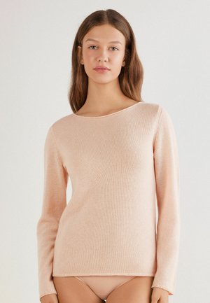 Pull en tricot rose clair à manches longues avec un col rond et une texture douce. Possède des détails de couture subtils le long de l'ourlet et des manches.