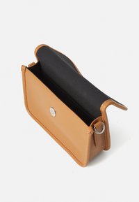 Tan läder crossbody-väska med ett silverknäpp. Funktioner en svart tyginteriör och en sidoring för att fästa en rem.