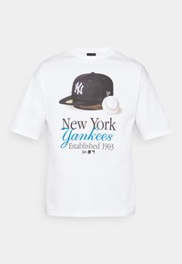 Camiseta de algodón blanca con un gráfico de una gorra negra de los New York Yankees y una pelota de béisbol, con "New York Yankees Established 1903" impreso en azul y negro.