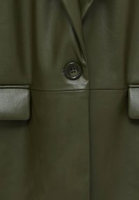 Manteau en similicuir vert olive avec un bouton, de larges revers et des poches structurées. Texture lisse avec un design moderne.