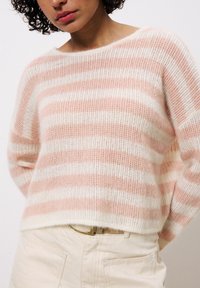 Gestreifter Pullover aus weichem pink und weißem Stoff, mit lockerer Passform, weitem Ausschnitt und strukturiertem Strickmuster. Der Saum endet auf Taillenhöhe.