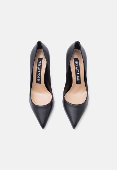 Μαύρες δερμάτινες γόβες με μυτερή μύτη και μπεζ εσωτερική επένδυση, με ετικέτες της μάρκας «sergio rossi» μέσα σε κάθε παπούτσι.