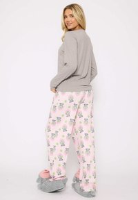 Haut à manches longues gris associé à un pantalon de pyjama rose avec un design de raton laveur cartoon. Des chaussons en pilou gris compl�ètent le look.
