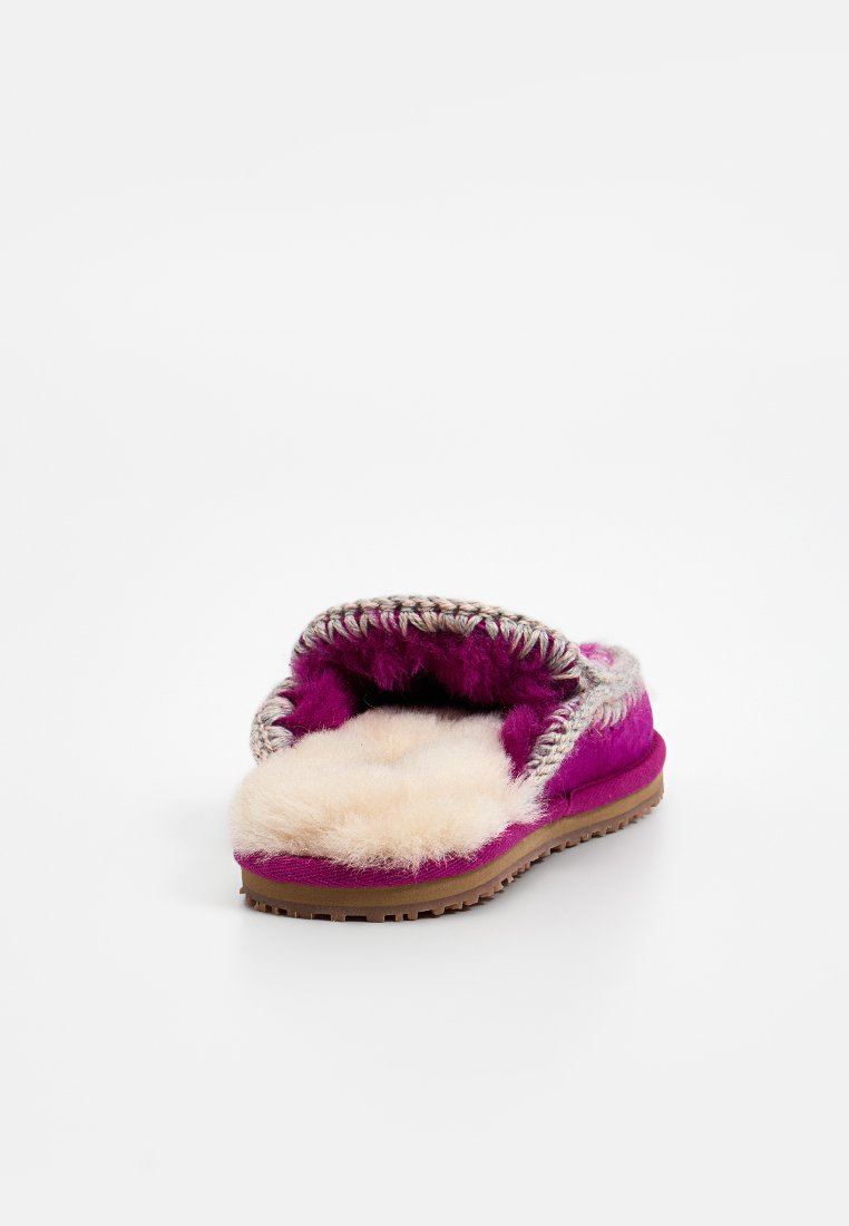 Fuchsia Slipper mit flauschigem Innenleben und geflochtenem Rand. Weiches Wildledermaterial, offener Rücken, Lammfellfutter, flache Gummisohle.