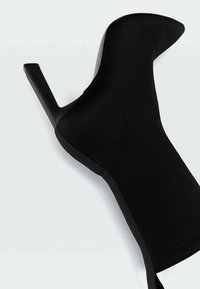 Botte noire à talon haut avec bout pointu et design élégant. Fabriquée en tissu lisse avec une finition satinée et un talon aiguille haut.