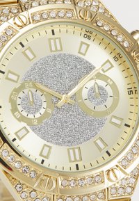Montre-bracelet en or avec un cadran en argent scintillant, deux sous-cadrans plus petits, des index en chiffres romains et des accents en cristal sur la lunette.