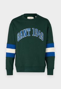 Sweatshirt vert avec "GANT 1949" imprimé en bleu. Présente des accents rayés bleus et blancs sur les manches. Fabriqué en tissu mélangé de coton.