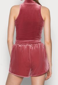 Velvet tvådelat set med ärmlös topp med hög krage och shorts med elastisk midja i rosafärg, som framhäver en slät textur och lyster.