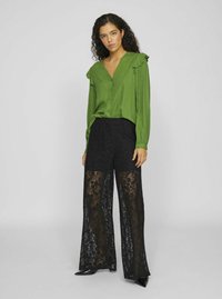 Green button-up blouse with ruffled shoulders, paired with high-waisted black lace wide-leg pants featuring floral patterns and a sheer texture.