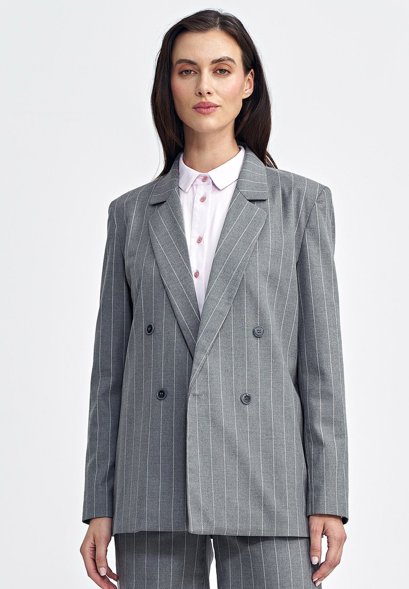 Szary, w paski, dwurzędowy żakiet z klapami, z czarnymi guzikami i gładką fakturą, noszony na jasnoróżowej koszuli z kołnierzykiem.