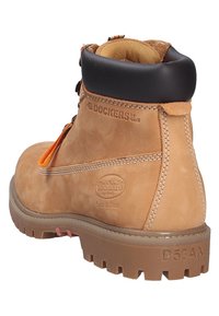 Braune Wildleder-Ankleboots mit einem schwarzen gepolsterten Kragen, orangefarbener Schnürung und einer strapazierfähigen Gummisohle mit tiefen Profilen; Logo auf der Seite geprägt.