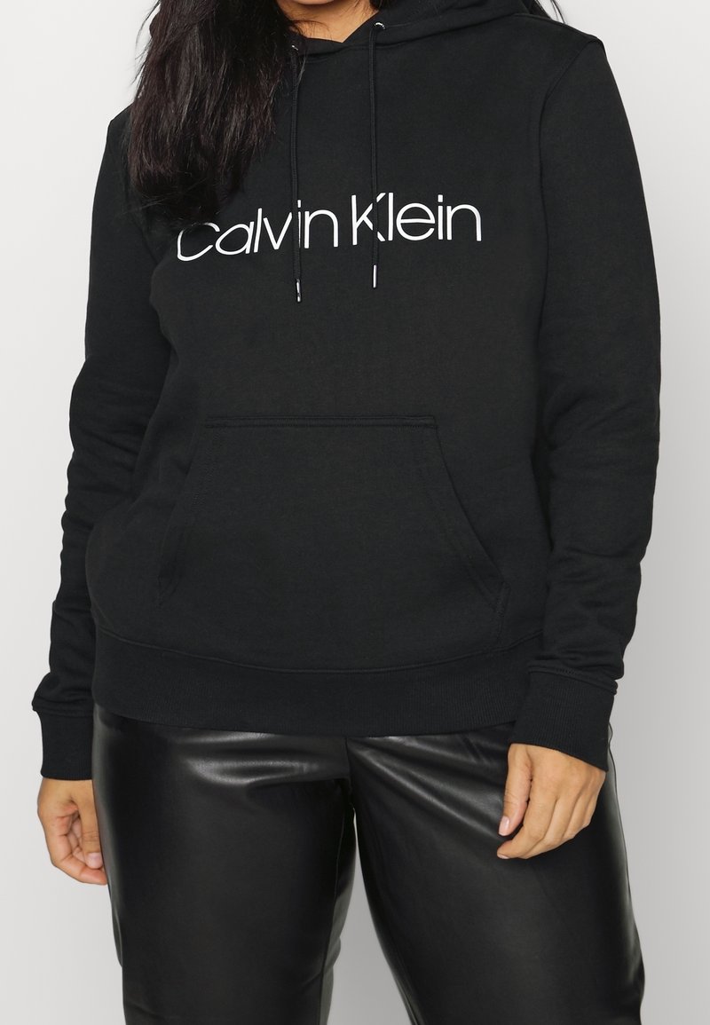 Felpa nera in cotone con logo bianco "Calvin Klein", tasca a marsupio frontale, cordini regolabili e polsini e orlo a costine.