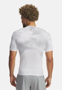 Witte, nauwsluitende sportshirt met korte mouwen, gladde textuur en logo op de achterkant. Het ontwerp beschikt over een naadloos patroon en strategische panelen.