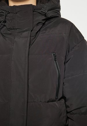Schwarze gepolsterte Jacke mit hohem Kragen, verstellbarem Kordelzugkapuze und einer Reißverschluss-Brusttasche. Glatte Textur mit gesteppten Details.