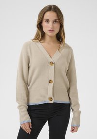 Beige knit cardigan featuring a V-neck, three wooden buttons, ribbed cuffs with light blue accents, and a textured body.