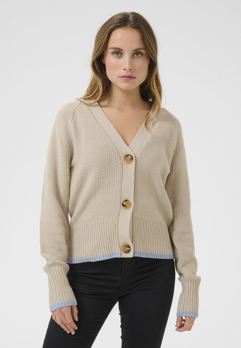 Beige knit cardigan featuring a V-neck, three wooden buttons, ribbed cuffs with light blue accents, and a textured body.