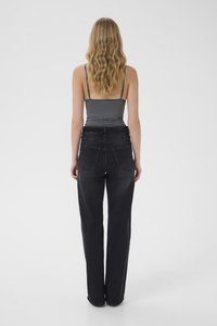 Black high-waisted jeans with a straight leg cut, featuring two back pockets and a smooth, slightly textured fabric. Grey fitted tank top.
