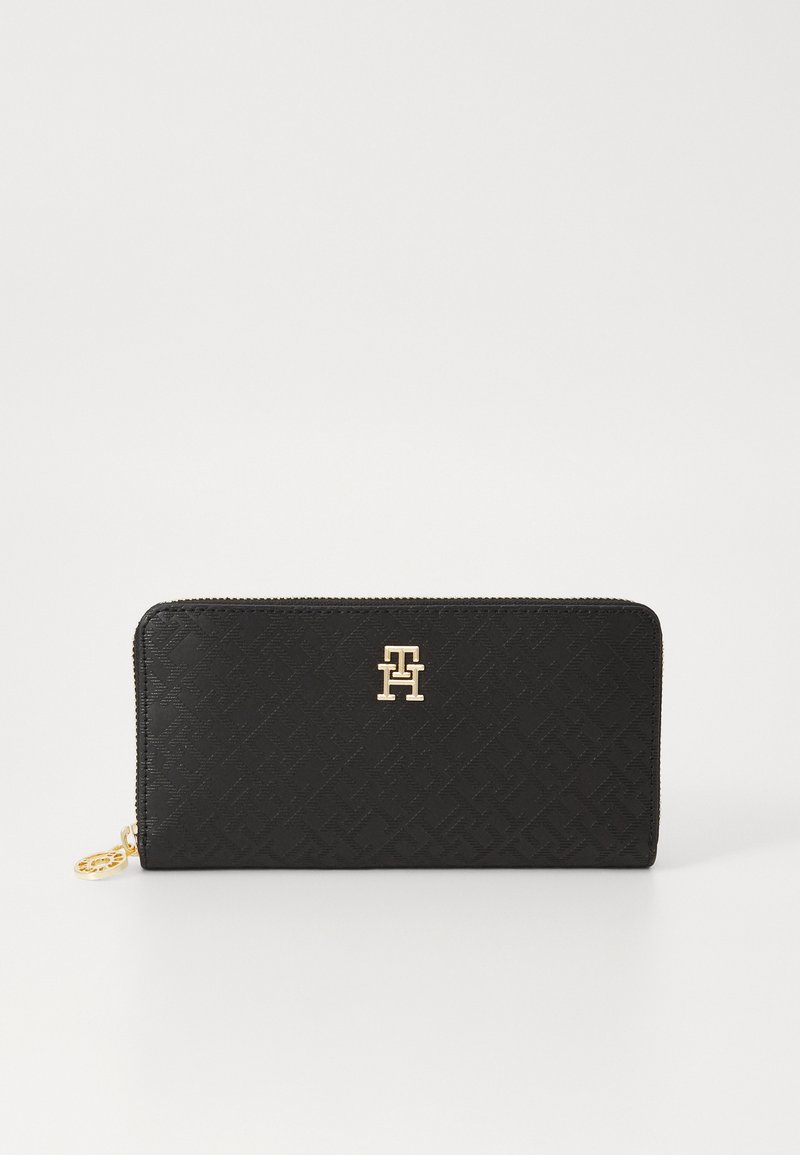 Black zippered wallet made of textured material featuring a gold logo accent on the front and geometric pattern.