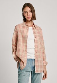 Geruite shirt in perzik, beige en wit. Heeft een ontspannen fit, een enkele borstzak en een knoopsluiting aan de voorkant. Lichtgewicht stof.