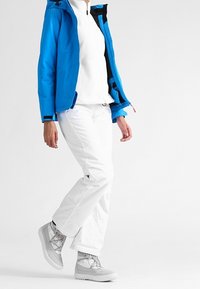 Blau wasserfeste Jacke, weiße mittlere Schicht, weiße Hose und graue Stiefel. Die Stiefel haben ein schlankes Design mit Schnürsenkeln; das Outfit ist für kaltes Wetter geeignet.