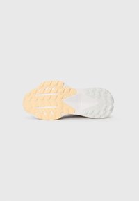 Semelle de chaussure de course présentant un design texturé, principalement blanche avec une section en caoutchouc de couleur orange clair, et des motifs de traction multidirectionnels.