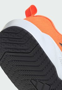 Oranžová sportovní obuv s texturovaným síťovaným svrškem, bílou mezipodešví a černou gumovou podešví s cik-cak vzorem tread.