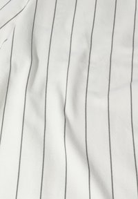 Tissu blanc avec des rayures verticales noires ; texture douce avec de légers plis, présentant un motif de lignes régulièrement espacées.