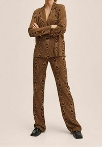 Abito a due pezzi marrone con motivo a onde in tonalità più chiare, realizzato in tessuto liscio. Caratterizzato da una vestibilità sartoriale e maniche lunghe.