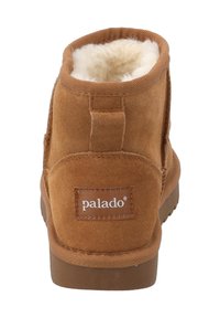 Botines de ante marrón con un forro cremoso y suave, suela de goma plana y una etiqueta de marca cosida en la parte trasera. Punta redondeada y cuello acolchado.