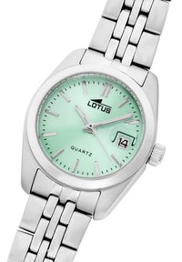 Reloj de cuarzo plateado con una esfera verde menta, marcadores de hora plateados y visualización de fecha. Presenta una pulsera de eslabones de acero inoxidable.