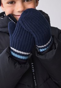 Tengerészkék kötött kesztyű bordázott mintával, a csuklónál vízszintes csíkokkal kék, fehér és sötétkék színekben, fekete kabáthoz viselve.