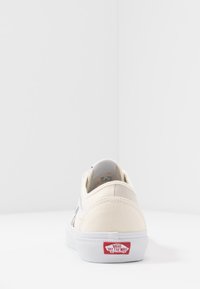 Canvas sneakers with a cream and gray color scheme, featuring a white sole and a red "Off the Wall" logo on the heel. Classic low-top design.
