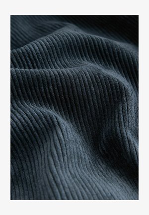 Donkerblauwe stof met een ribbeltextuur, waarin verticale lijnen een zachte, pluchen uitstraling creëren. De stof is dik en uitnodigend.