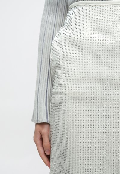 Γκρι μακρυμάνικη μπλούζα με ριμπ ύφανση σε συνδυασμό με ασημί φούστα με διατρήσεις, που αναδεικνύει εφαρμοστή γραμμή και υφή με διακριτική λάμψη.