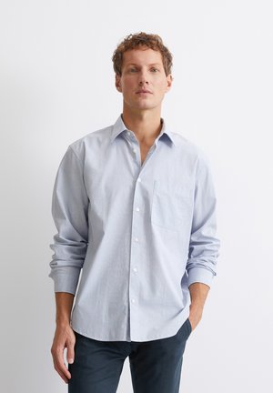 Light blue long-sleeve shirt made of cotton, featuring a button-down collar, front pocket, and buttoned cuff details. Smooth texture.
