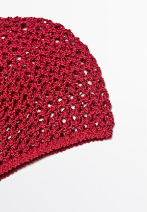 Rødt hæklede stofstykke med et hulmønster, vist på en hvid baggrund.