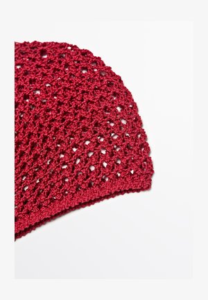 Rødt hæklede stofstykke med et hulmønster, vist på en hvid baggrund.