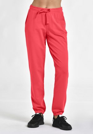 Lysende pink atletiske joggere med snor i taljen, elastiske manchetter og sidelommer, parret med sorte atletiske sko.