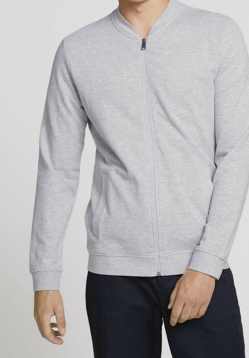 Gray zip-up sweatshirt made of soft fabric, featuring a round neckline, long sleeves, side pockets, and ribbed cuffs.