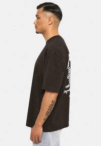 Black cotton t-shirt with a relaxed fit, short sleeves, and a white graphic design on the back. Features a crew neck and soft texture.