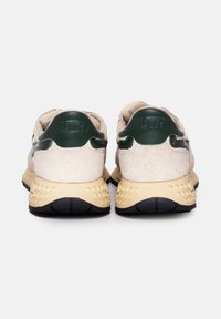 Sneaker con una toma in suede beige, dettagli in pelle verde e una suola intermedia beige texturizzata con battistrada in gomma nera per la presa.