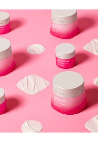 Estee Lauder Nutritious smeltende crème/maskeerpotten in roze verloop met witte deksels, tentoongesteld op een roze achtergrond, vergezeld van crèmemonsters.