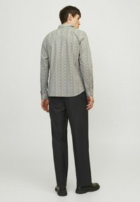 Mo�ška srajca z dolgimi rokavi v vzorčasti tkanini, z ovratnikom, slim fit krojem in gumbi na manšetah, v kombinaciji z oblikovanimi temnimi hlačami.