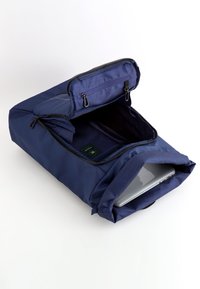 Mörkblå ryggsäck med dragkedja upptill, öppen för att avslöja ett rymligt inre där en laptop är delvis synlig. Slät tyg med subtil textur.