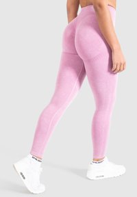 Leggings rosa a vita alta con una finitura testurizzata. Presentano dettagli a coste e cuciture. Abbinati a sneaker bianche.