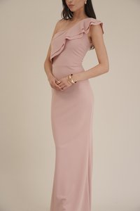 En-skulder rosa kjole med volanghals, tettsittende silhuett og glatt tekstur. Gullarmbånd båret på håndleddet. Elegante designdetaljer.