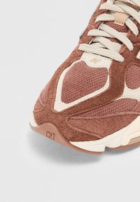 Baskets en daim marron et en mesh avec des accents crème, bout rond, dessus texturé et lacets plats. Comprend une semelle en caoutchouc avec une marque.