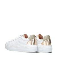 Baskets blanches avec une tige en cuir lisse, un talon doré métallique et un accent doré pailleté. La semelle blanche épaisse offre un contraste et du confort.